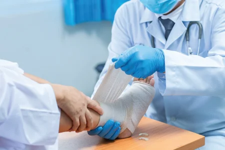Doctor applying bandage to injured foot representing TRAUMA, FRACTURES & POLYTRAUMA – Advanced Orthopedic Trauma Care in Gurgaon by Dr. (Prof.) Ravi Sauhta